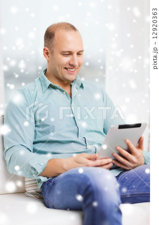 smiling man with tablet pc sitting on couch 12920363
