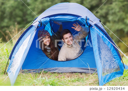 smiling couple of tourists looking out from tent smiling couple of tourists looking out from tent 12920434