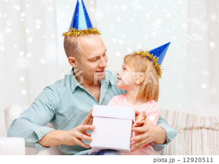 father and daughter in party caps with gift box 12920511