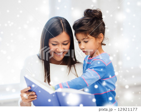 mother and daughter with book indoors 12921177