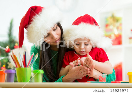 child and mom in Santa hats making christmas tree of plasticine 12922975
