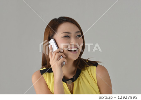 Asian lady laughing while talking on a smart phone 12927895
