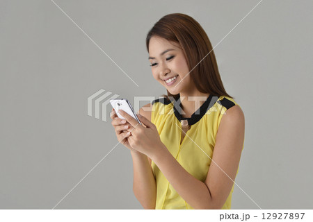 Asian lady texting with mobile phone Asian lady texting with mobile phone 12927897