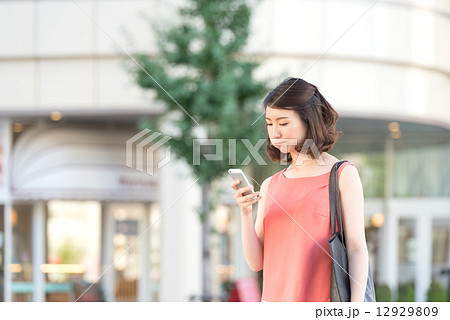 スマートフォンを見てふくれっ面をする女性 12929809