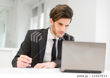 Businessman sitting at his laptop and working in the office 12947614