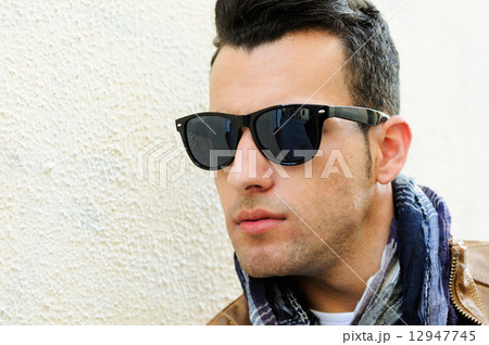 Attractive man wearing tinted sunglasses in urban background Attractive man wearing tinted sunglasses in urban background 12947745