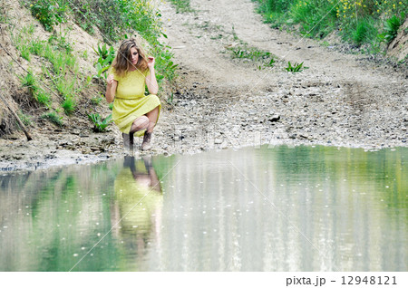 Beautiful blonde girl, dressed with a green dress, near a lake 12948121