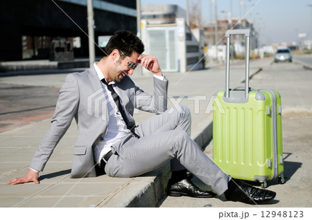 Man dressed in suit and suitcase sitting on the floor in the str 12948123