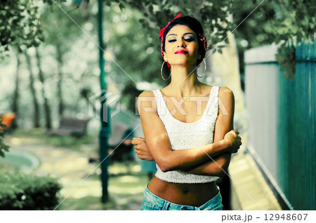 Pin-up girl. American style, in a garden, wearing jeans and t-sh 12948607