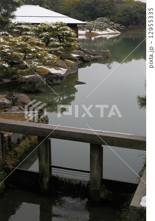 冬の栗林公園、南湖と西湖をつなぐ水路の堰付近から見た掬月亭と南湖 12955335