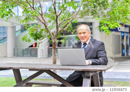Senior Asian businessman connecting to his business using mobile device at outdoor  12956873