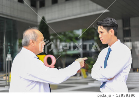 Two Asian men in shirt and tie in dispute with the older man pointing finger at the younger man Two Asian men in shirt and tie in dispute with the older man pointing finger at the younger man 12959390