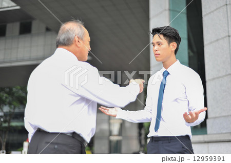 Two Asian men in shirt and tie in dispute with the older man pointing finger at the younger man Two Asian men in shirt and tie in dispute with the older man pointing finger at the younger man 12959391