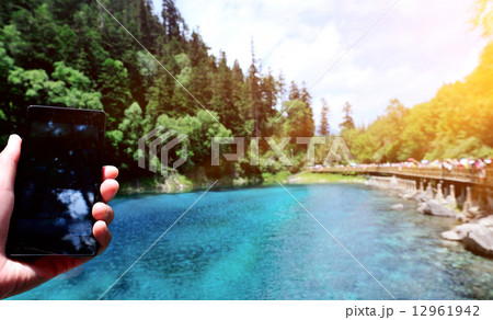 woman tourist hand taking photo with smart phone on jiuzhaigou national park, china woman tourist hand taking photo with smart phone on jiuzhaigou national park, china 12961942
