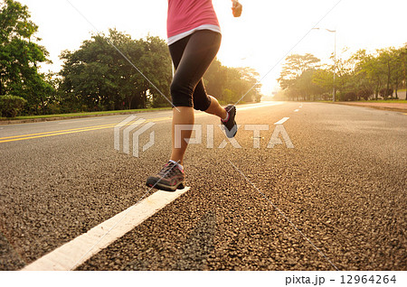 young fitness woman running at sunrise road 12964264