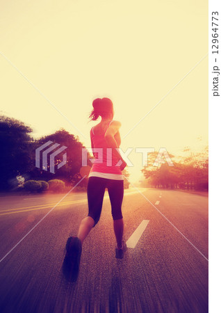 young fitness woman running at sunrise road 12964773