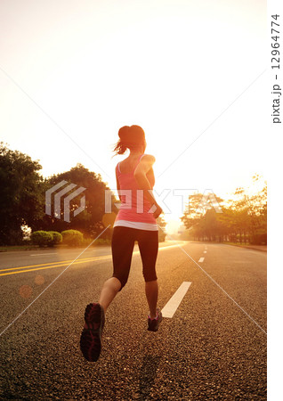 young fitness woman running at sunrise road 12964774