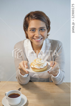 Asian lady enjoying her coffee and dessert at a cafe. 12980175