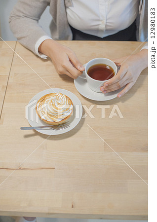 Asian lady enjoying her coffee and dessert at a cafe. 12980183