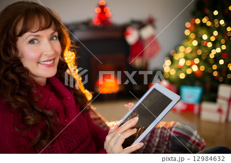 Cheerful redhead using tablet at christmas Cheerful redhead using tablet at christmas 12984632