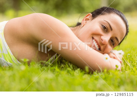 Smiling brunette lying on grass Smiling brunette lying on grass 12985115