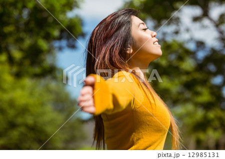 Beautiful woman with arms outstretched in park 12985131
