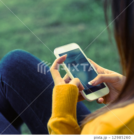 Woman text messaging in park 12985260