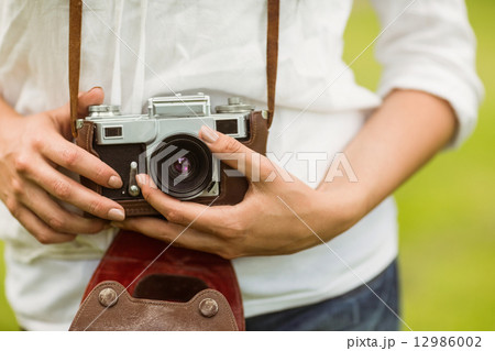 Mid section of woman holding vintage camera 12986002