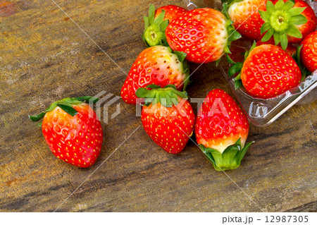 Close up of fresh strawberries on the table and inside plastic b 12987305