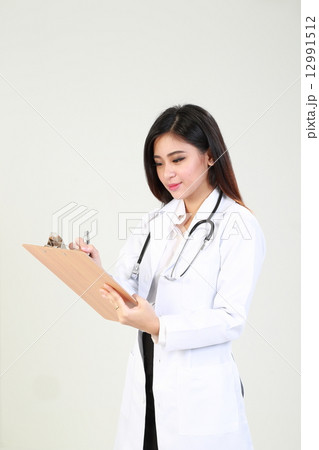 Lady doctor writing report on clipboard  12991512