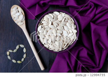 a bowl with toasted pumpkin seeds and wooden spoon 12994735