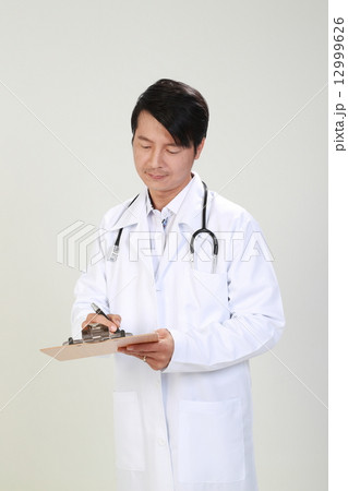 Male Doctor Writing Report on Clipboard 12999626