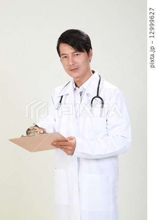 Male Doctor Writing Report on Clipboard Faceing Forward 12999627