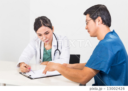 Surgeon and medical doctor discussing whilst referring to documents Surgeon and medical doctor discussing whilst referring to documents 13002426