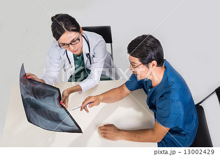 Surgeon and medical doctor discussing whilst referring to x-ray film Surgeon and medical doctor discussing whilst referring to x-ray film 13002429