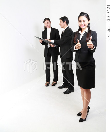 Woman in front both thumbs up man and woman discuss at back Woman in front both thumbs up man and woman discuss at back 13012421