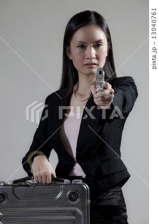 Asian female holding briefcase & gun 13040761