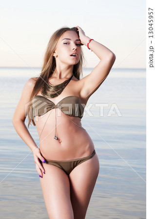 Beautiful woman at dawn on the beach 13045957