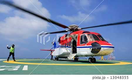The helicopter landing officer give signal to passenger to embar The helicopter landing officer give signal to passenger to embar 13048355