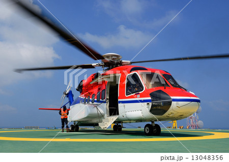 The helicopter is landing to embark passenger at oil rig platfor 13048356