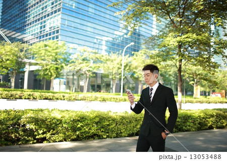 Business man looking at phone while walking 13053488