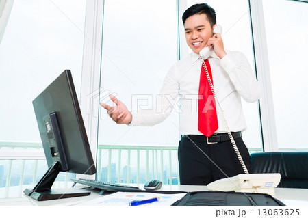 Asian businessman  on phone working in office 13063625