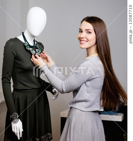 Young woman looking at necklace on mannequin in showroom 13087710