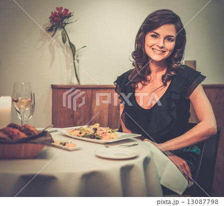 Beautiful young lady alone in restaurant 13087798