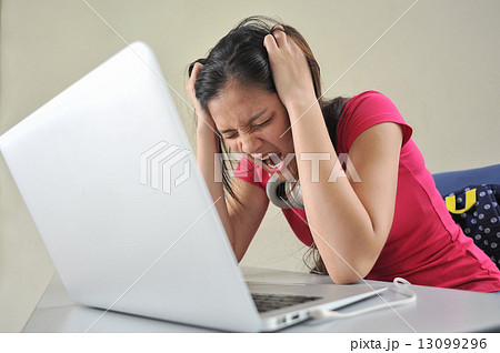 A young Asian female student feeling stressed over her school work / reseach in front of laptop A young Asian female student feeling stressed over her school work / reseach in front of laptop 13099296
