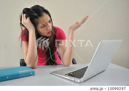 A young Asian female student feeling stressed over her school work / reseach in front of laptop A young Asian female student feeling stressed over her school work / reseach in front of laptop 13099297