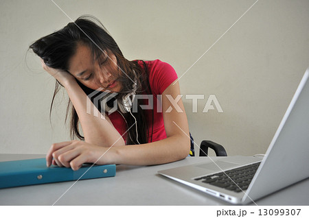 A tired young female Asian student fall asleep at her desk in the classroom in front of laptop A tired young female Asian student fall asleep at her desk in the classroom in front of laptop 13099307