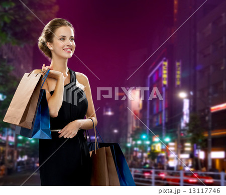 smiling woman in evening dress with shopping bags 13117746