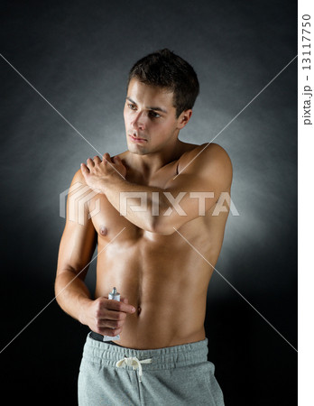 young male bodybuilder applying pain relief gel 13117750