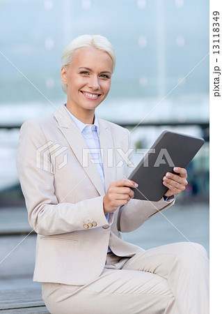 smiling businesswoman with tablet pc outdoors 13118349